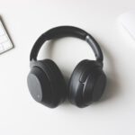 black wireless headphones between Apple Keyboard and Apple Magic Mouse on white surface